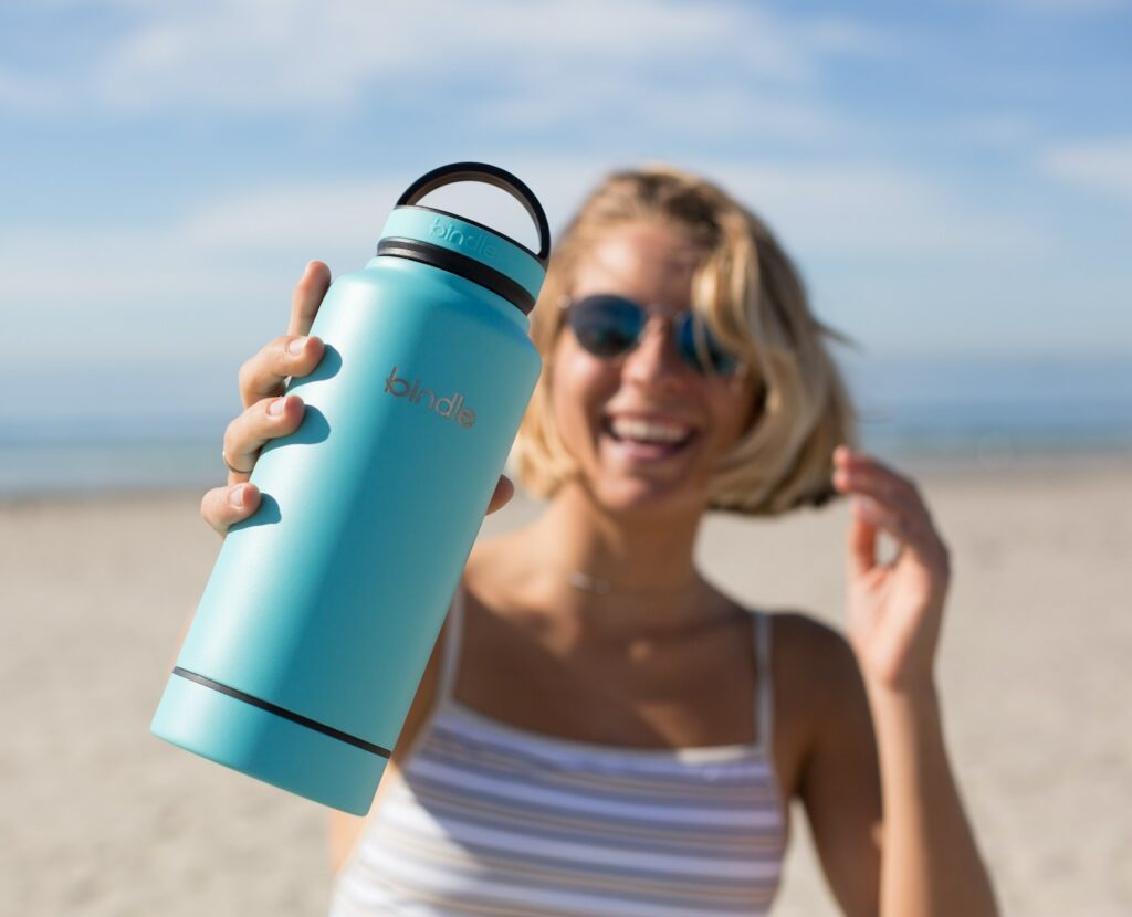 woman in white tank top holding blue and black tumbler