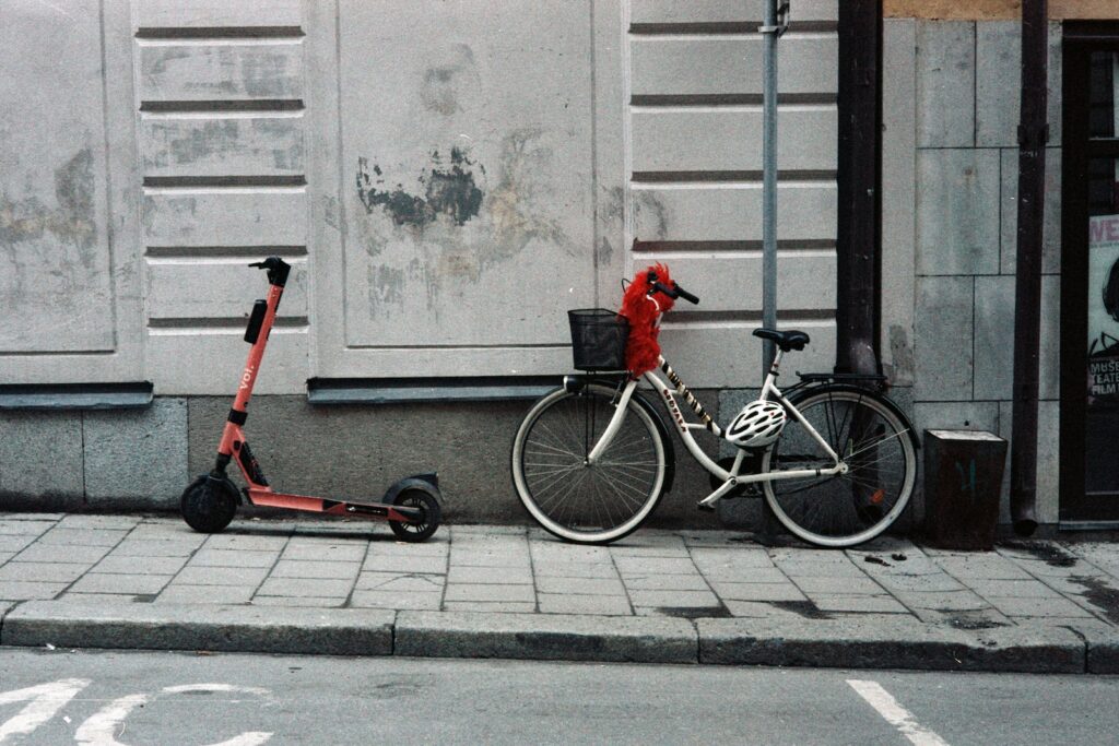 red and black bicycle with training wheels beside white wall
