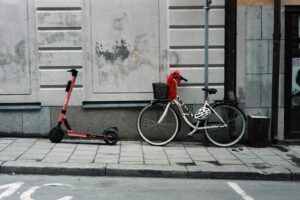 red and black bicycle with training wheels beside white wall