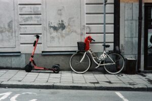 red and black bicycle with training wheels beside white wall